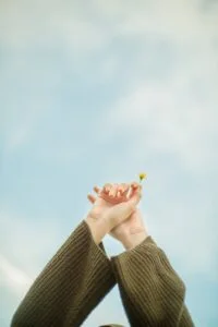 woman holding tiny flower in raised arms