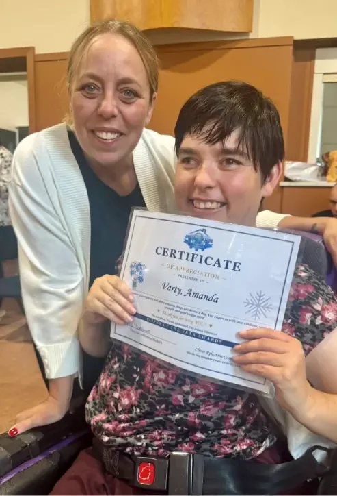 A client proudly holding a certificate of appreciation with a staff member