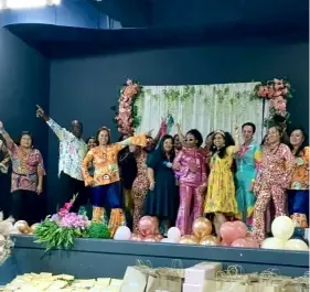 Staff members performing a dance and song tribute for clients on stage