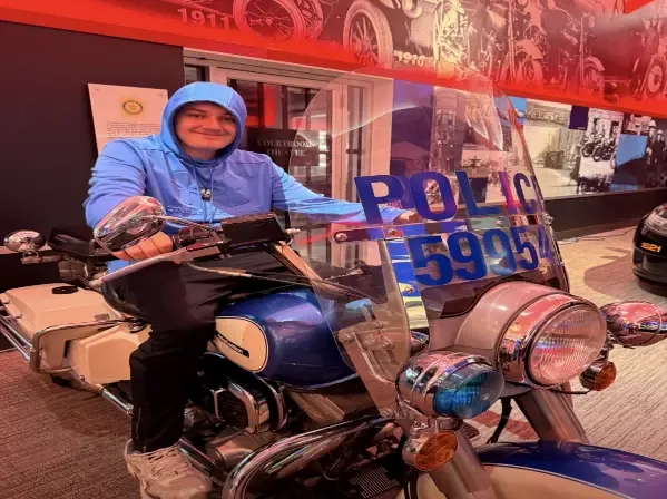 A client sitting on a Calgary Police Service motorcycle during a community visit