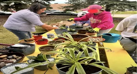Clients potting plants together at an outdoor gardening table