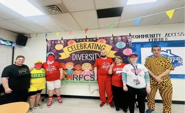 Clients and staff in colourful outfits in front of the Celebrating Diversity banner